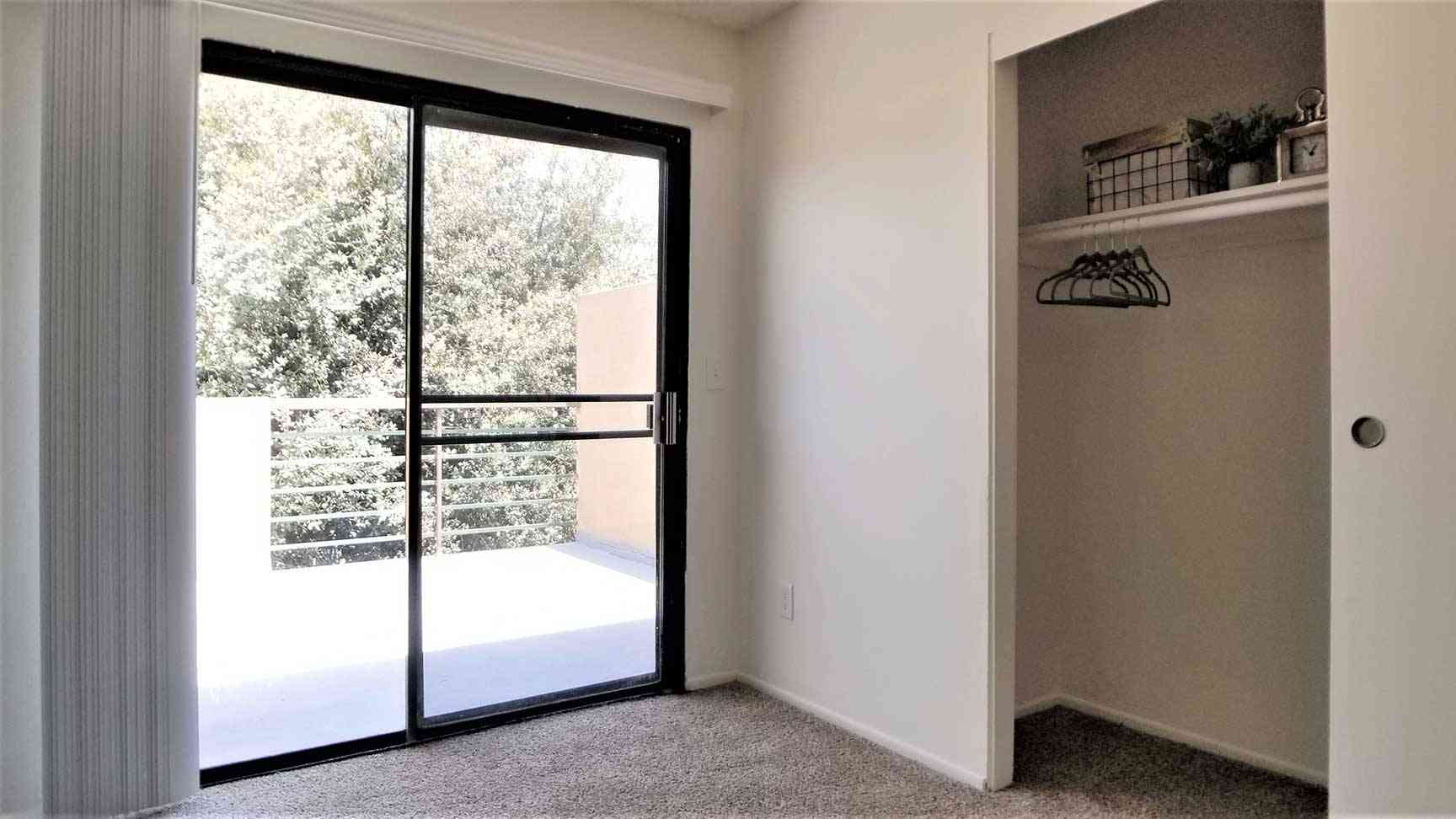 bright bedroom with closet and private balcony view