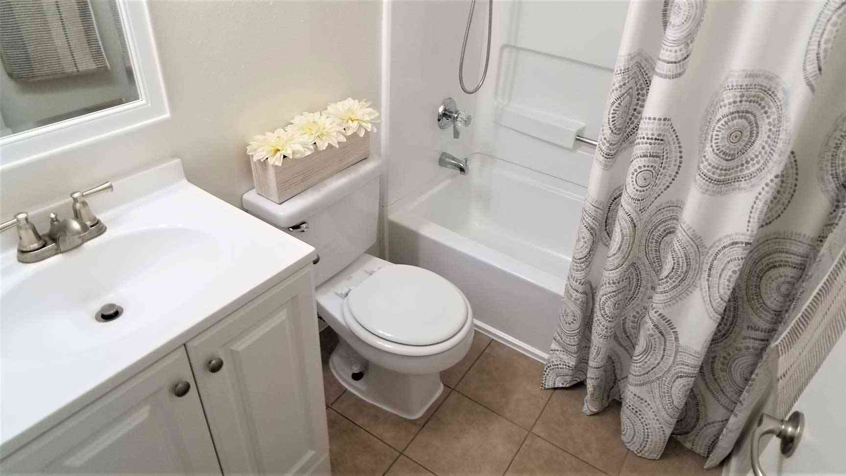renovated bathroom with white vanity and tile flooring